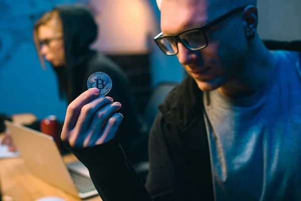 Close-up shot of young handsome hackers holding bitcoin — Stock Photo