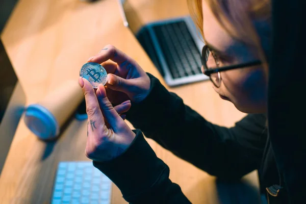 Close-up shot of young female hacker holding bitcoin — Stock Photo