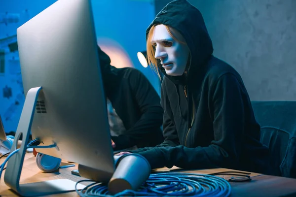 Hacker in maschera che lavora con il computer per sviluppare malware — Foto stock