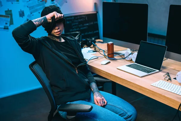 Giovane hacker femminile sul posto di lavoro togliersi la maschera — Foto stock