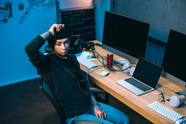 Jovem hacker feminino na frente da mesa a tirar a máscara — Fotografia de Stock