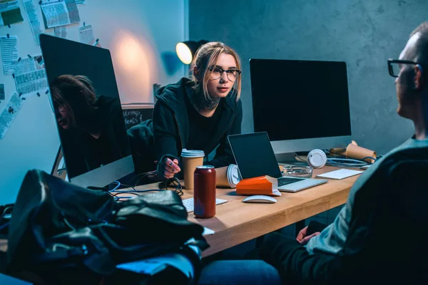 Couple of hackers talking at workplace in dark room — Stock Photo