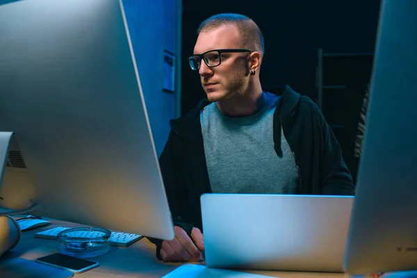 Young hacker developing malware in dark room — Stock Photo