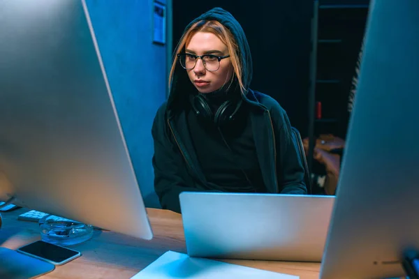 Young hooded female hacker developing malware — Stock Photo