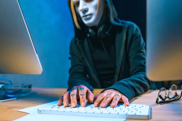 Close-up shot of masked female hacker with tattoos on hands developing malware — Stock Photo