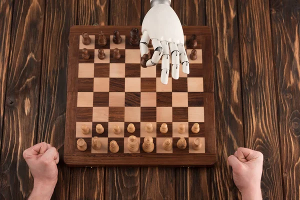 Abgeschnittene Aufnahme eines Roboters, der Schach mit Menschen auf hölzerner Oberfläche spielt — Stockfoto