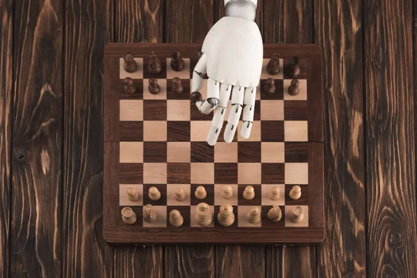 Cropped shot of robot playing chess on wooden surface — Stock Photo