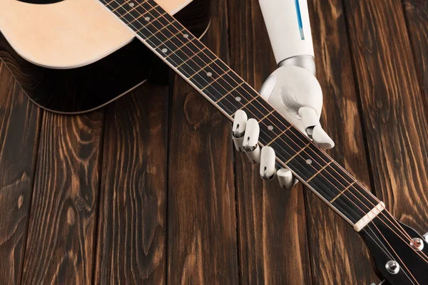 Plan recadré de robot jouant de la guitare acoustique sur une surface en bois — Photo de stock