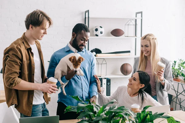 Homme d'affaires afro-américain tenant Jack Russell terrier et des collègues souriants debout près — Photo de stock