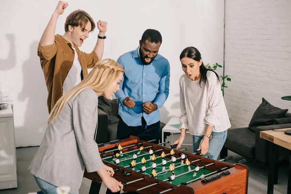 Due donne d'affari che giocano a calcio balilla e colleghi uomini che li rallegrano — Foto stock