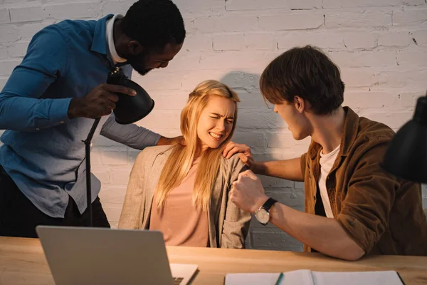 Two multicultural businessmen threatening and shine lamp in face of businesswoman — Stock Photo