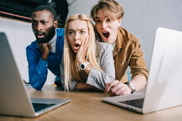 Shocked multicultural business colleagues watching on laptop screen — Stock Photo