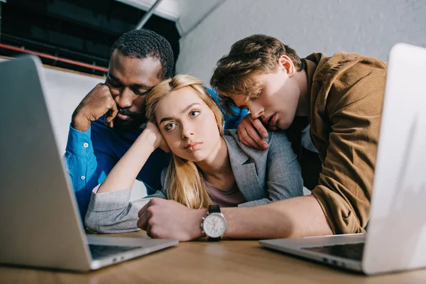 Tired businesswoman with two sleeping male colleagues on shoulders sitting at table — Stock Photo