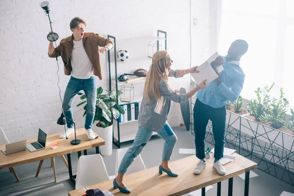 High angle view of multiethnic two colleagues fighting on table in modern office — Stock Photo