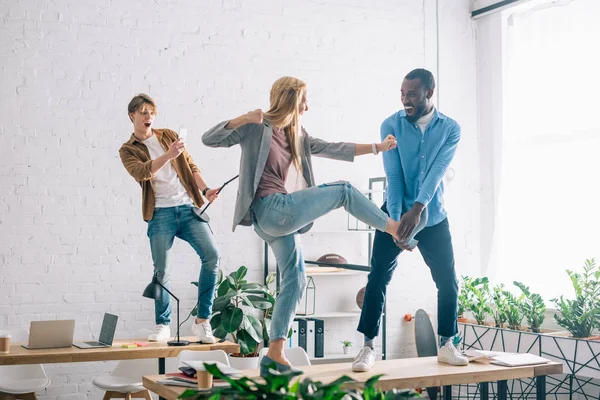 Businessman taking picture of multiethnic business colleagues fighting on table in modern office — Stock Photo