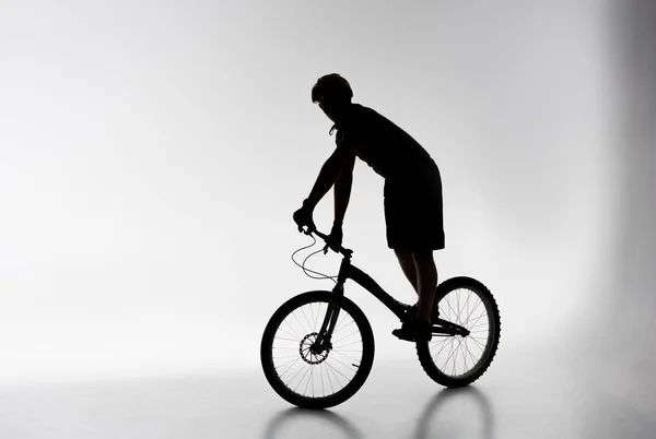 Silueta del ciclista de trial en casco equilibrado en bicicleta en blanco — Stock Photo