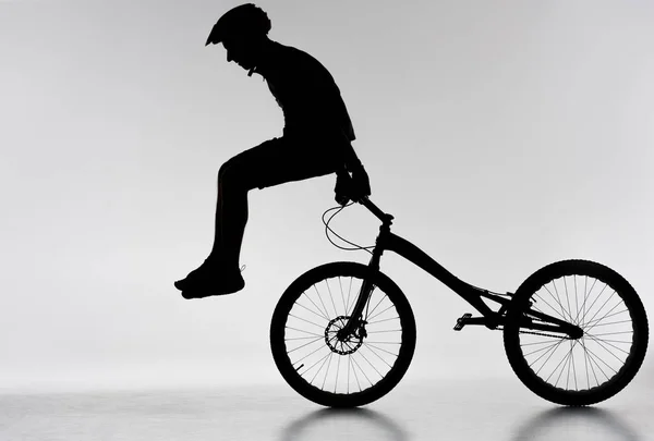 Silueta del motociclista de trial realizando acrobacias en bicicleta en blanco — Stock Photo