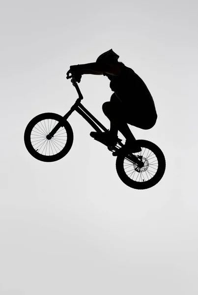 Silhouette of trial cyclist jumping on bicycle on white — Stock Photo