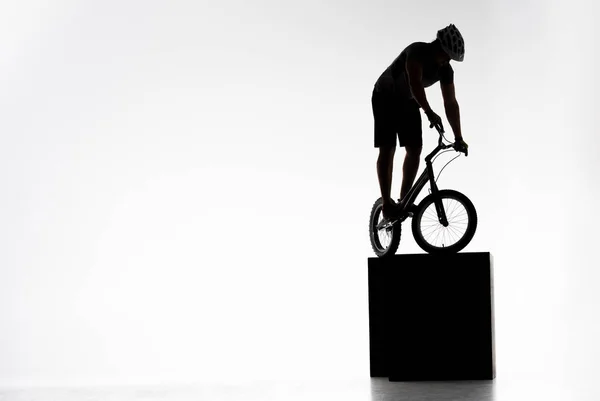 Silhouette of trial cyclist balancing on obstacles on white — Stock Photo