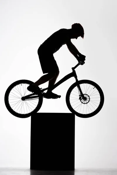 Silhueta de julgamento ciclista balanceamento em pé sobre branco — Fotografia de Stock