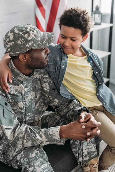 Soldado afroamericano abrazándose con su hijo - foto de stock