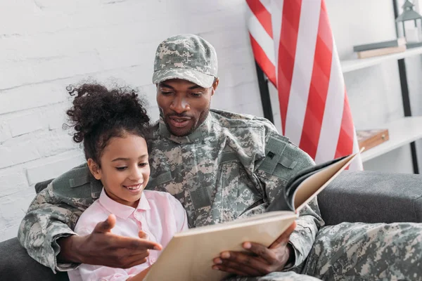 Male soldier reading book to his daughter — Stock Photo