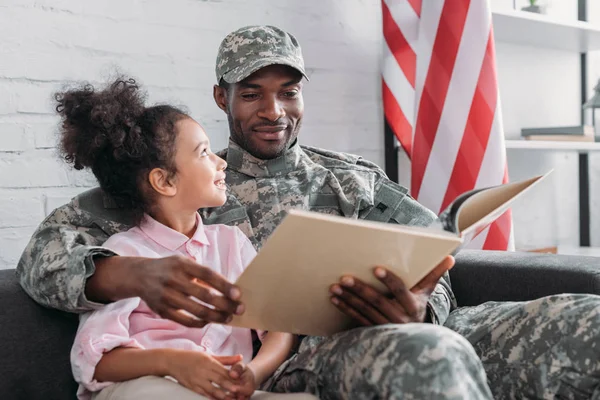 African american male soldier with daughter reading book — Stock Photo