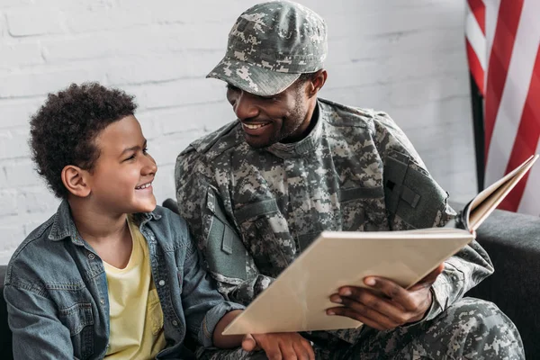African american man in camouflage clothes and boy reading book — Stock Photo