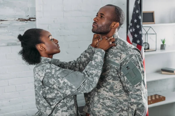 Donna afro-americana aiutare l'uomo a vestirsi in abiti mimetici — Foto stock