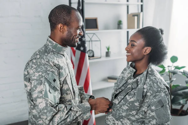 Handsome man helping woman to get dressed in camouflage clothes — Stock Photo