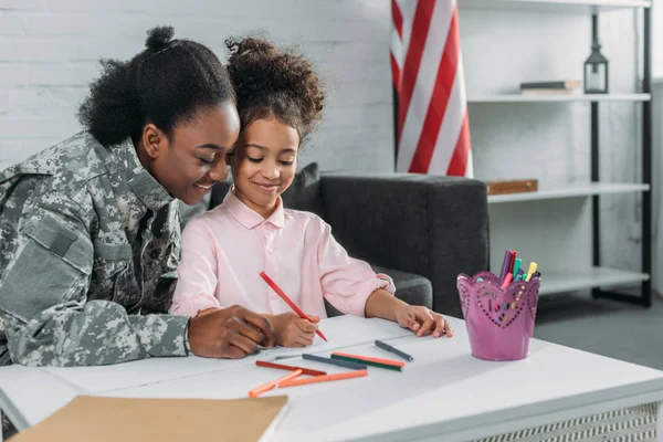 Mother army soldier and her daughter drawing together — Stock Photo