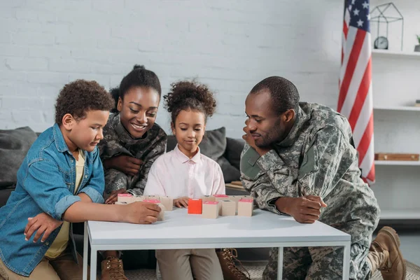 Femme et homme en uniforme de l'armée avec leurs enfants jouant jeu de mots — Photo de stock
