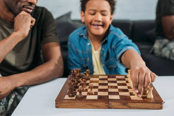 Père en uniforme de l'armée enseignant à son fils à jouer aux échecs — Photo de stock