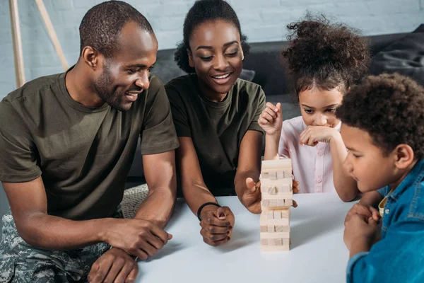 African american female and male soldiers with their children playing wooden blocks game — Stock Photo