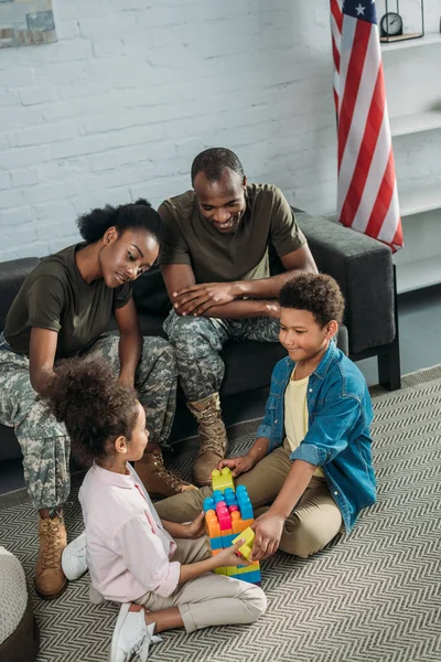 Femme et homme en uniforme de l'armée regardant leurs enfants jouer avec le constructeur — Photo de stock