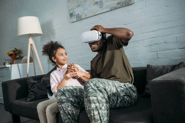 Padre en uniforme del ejército con hija afroamericana usando gafas vr - foto de stock