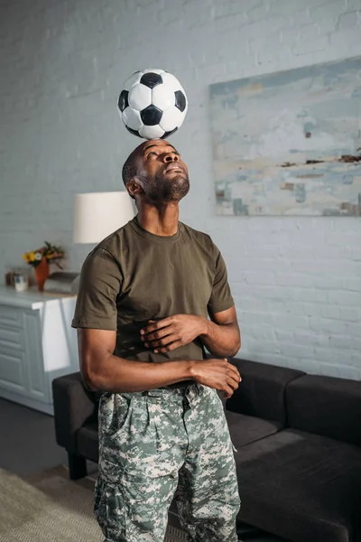 African american soldier playing with football ball on head — Stock Photo