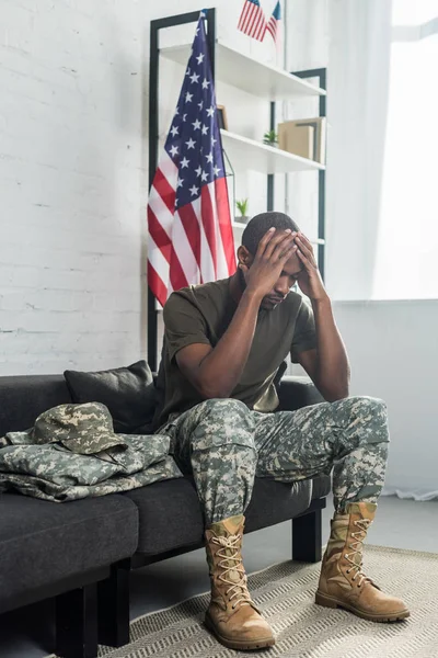 Soldado del ejército trastornado sentado en el sofá con ropa de camuflaje - foto de stock
