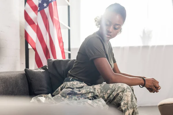 Female army soldier in camouflage clothes sitting on sofa — Stock Photo