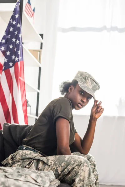 Jovem soldado em roupas de camuflagem sentado no sofá — Fotografia de Stock