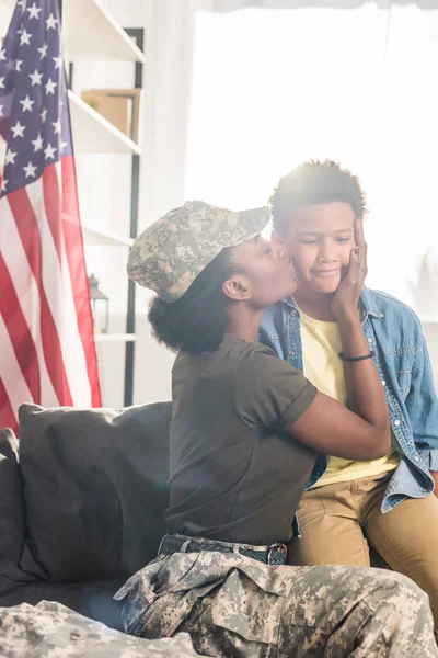 Soldado feminino em roupas de camuflagem beijando seu filho — Fotografia de Stock