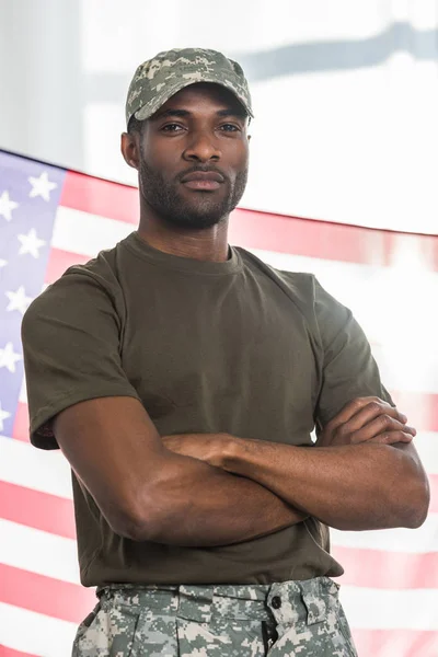 Soldado afroamericano con los brazos cruzados frente a nosotros bandera - foto de stock