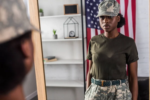 Female army soldier in camouflage clothes posing by the mirror — Stock Photo