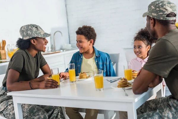 Parents in camouflage clothes with children enjoying meal in kitchen — Stock Photo