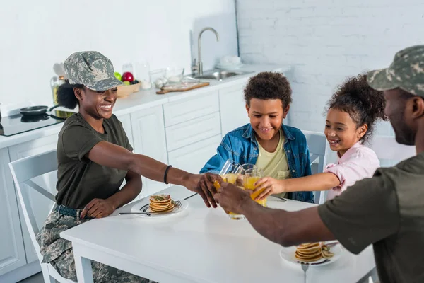 African american female and male soldiers and their children toasting with juice — Stock Photo