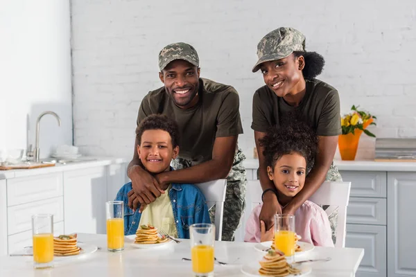Army soldiers with happy kids enjoying meal in kitchen — Stock Photo