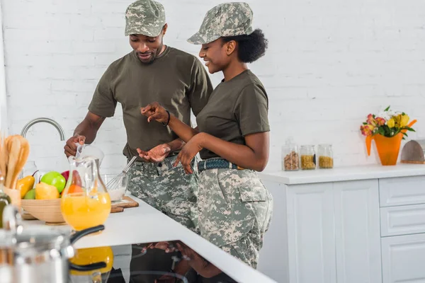 African american female soldier with man cooking together at home kitchen — Stock Photo