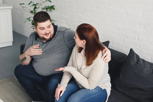 Sobrepeso namorado e tamanho mais namorada conversando e gesticulando no sofá em casa — Fotografia de Stock