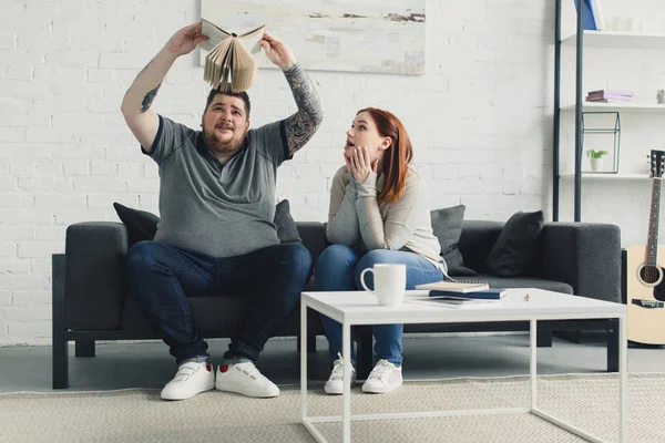 Boyfriend and girlfriend searching something in book at home — Stock Photo