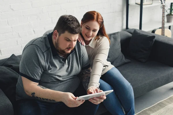Namorado e namorada assistindo algo em tablet em casa — Fotografia de Stock